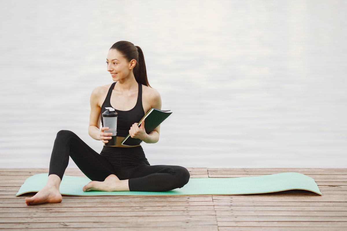 Pretty lady training in a summer park. Brunette doing yoga. Girl in a sportsuit.