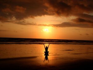 Woman doing somatic yoga with a sunset behind.